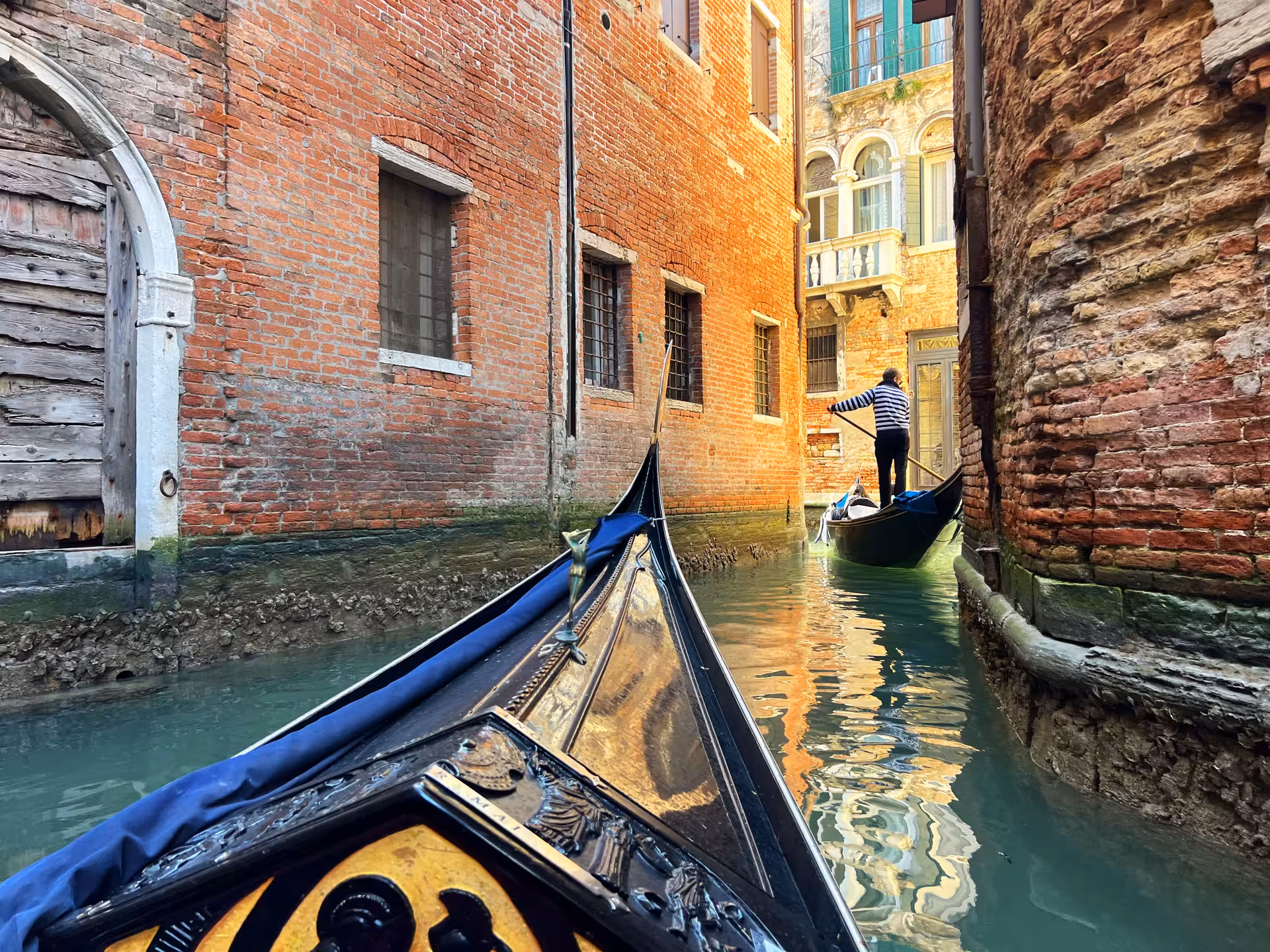Traditional gondola gliding through a narrow canal flanked by historic brick buildings in Venice.
