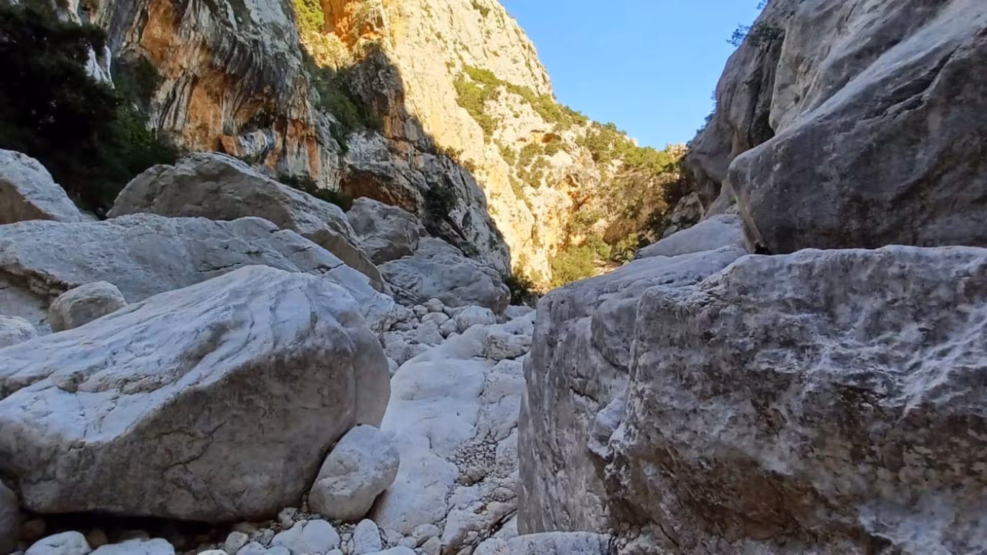 Majestic boulders line the rugged path in Gorropu Canyon, ideal for adventurous trekking enthusiasts.