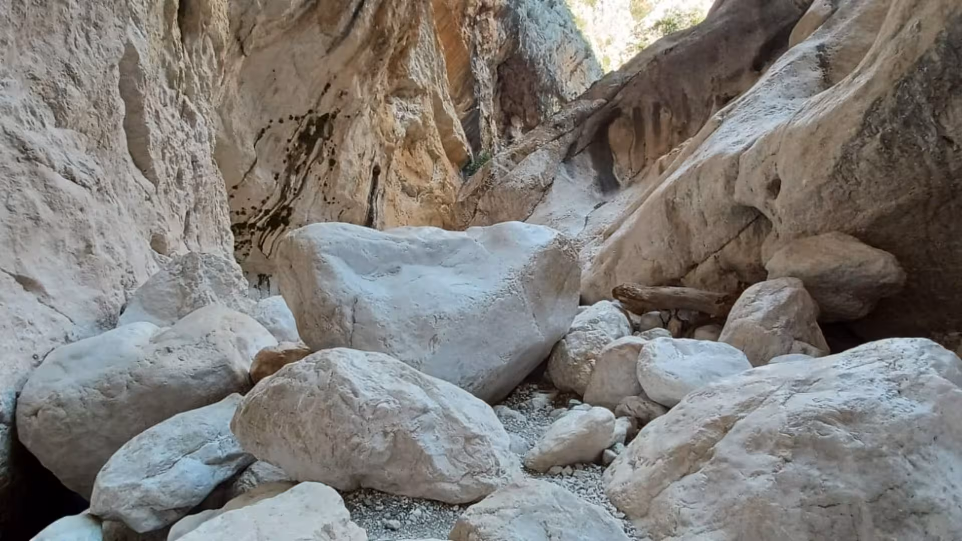 Imposing rocky walls and boulders create a dramatic atmosphere in Sardinia's Gorropu Canyon trail.