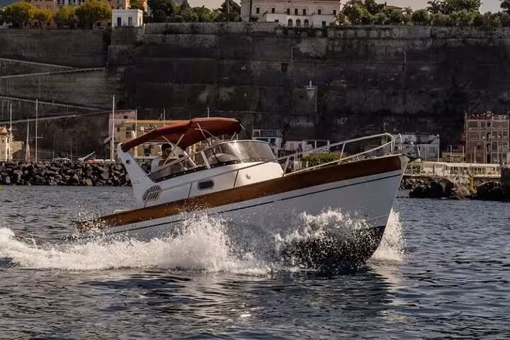 Gozzo 750 boat cruising near Sorrento's historic cliffs, offering a picturesque private tour to Positano and Amalfi.