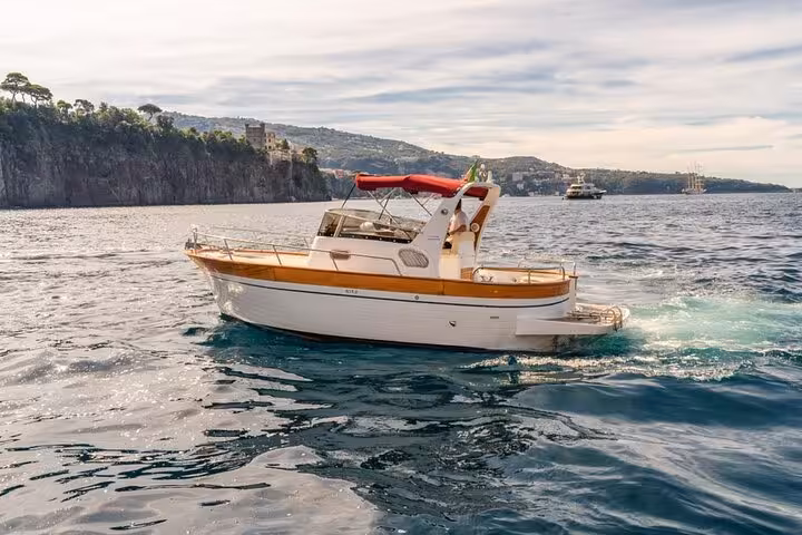 Scenic view of a typical Gozzo 750 boat cruising near the cliffs on a private Sorrento to Positano tour.