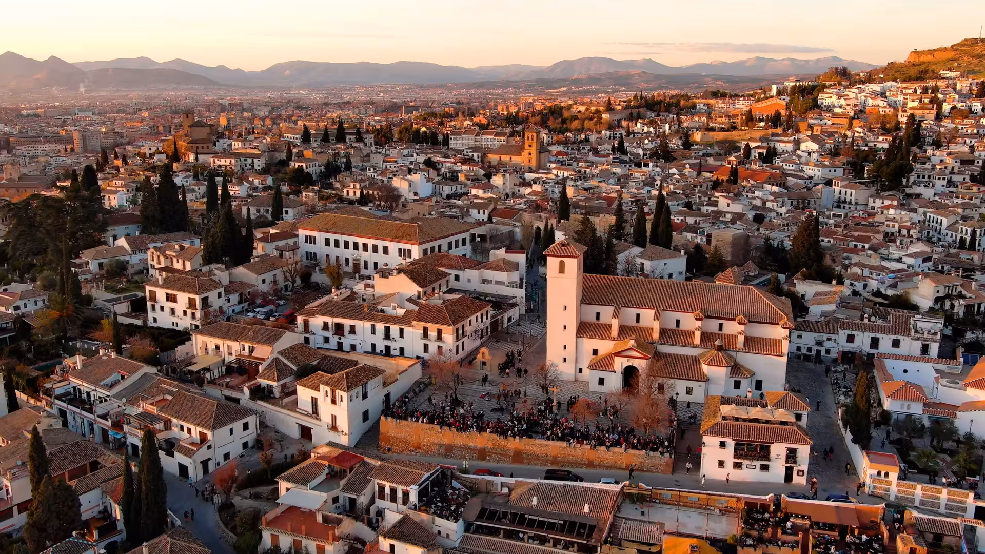Aerial view of Granada's Albaicín neighborhood at sunset, showcasing historic architecture and vibrant streets.