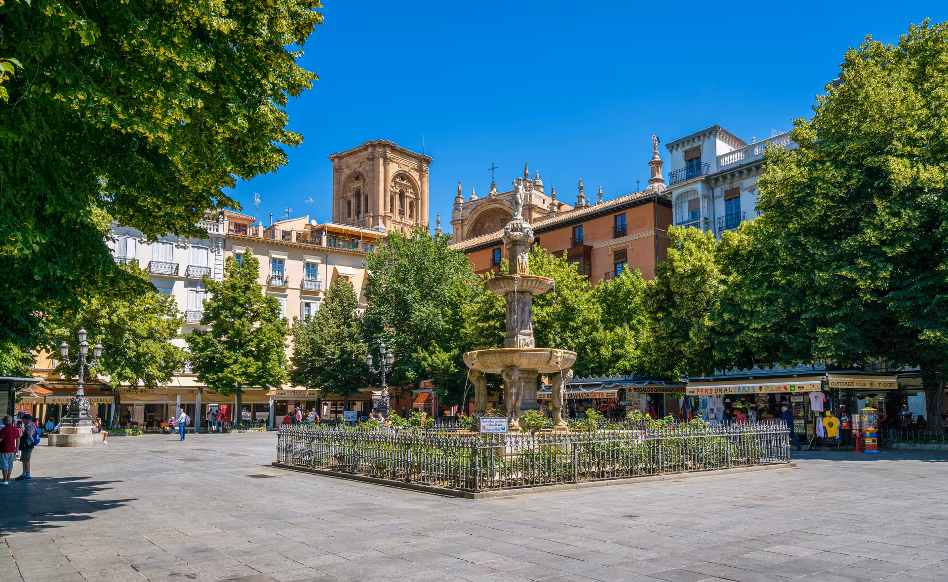 Scenic view of Granada's bustling square with historic architecture and a central fountain.