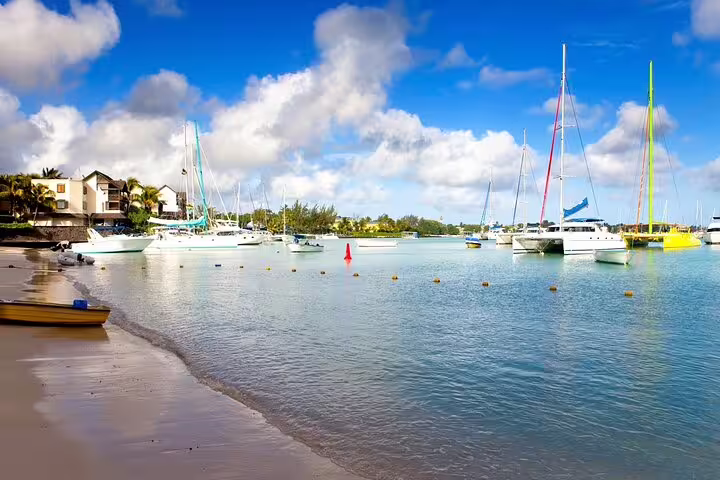 Grand Baie lagoon with sailboats and sandy shore, part of a private tailored North Mauritius full-day adventure
