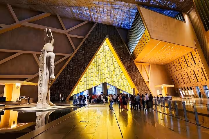 Grand Egyptian Museum entrance hall with towering statue and visitor group on half-day tour with lunch