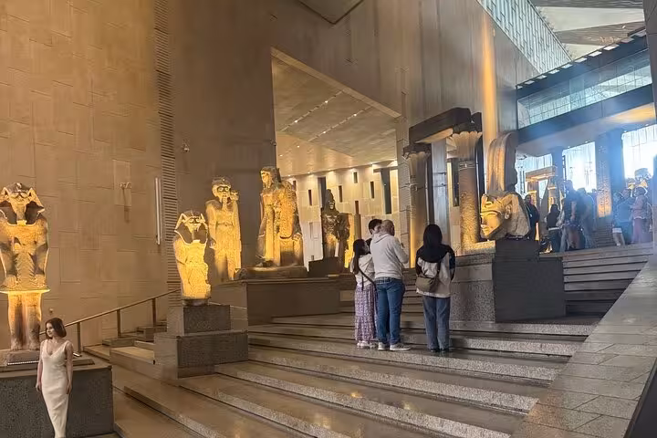 Grand Egyptian Museum entrance hall on private tour, with illuminated pharaoh statues and grand stairway