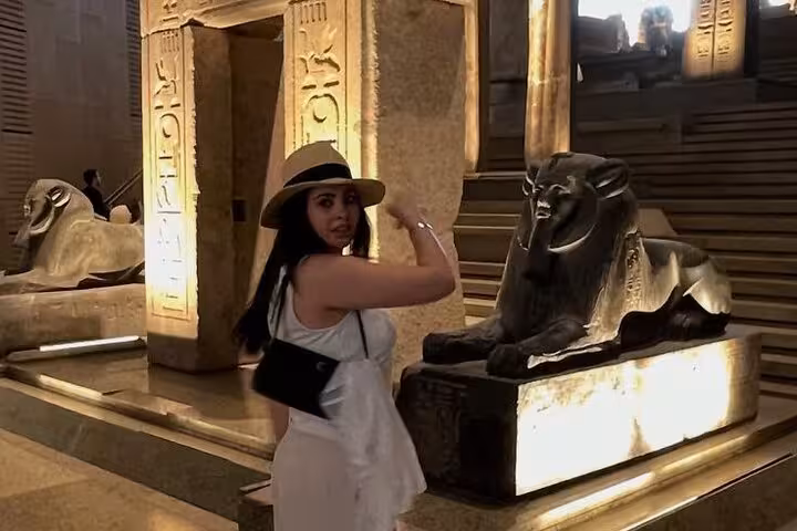 Traveler exploring Grand Egyptian Museum Giza beside sphinx-like statue, part of pyramids and lunch tour
