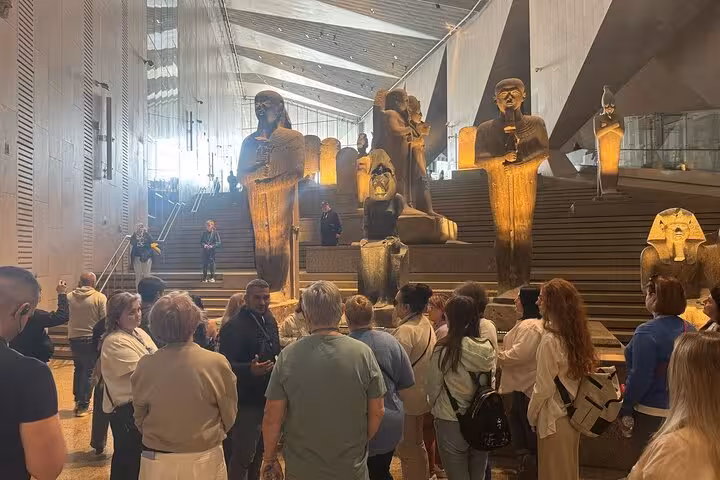 Guided private tour at the Grand Egyptian Museum, crowds viewing monumental statues on the grand staircase