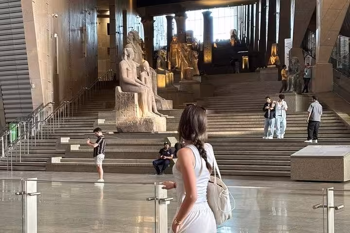 Visitors in the Grand Egyptian Museum main hall near monumental statues on half-day tour with lunch and tickets