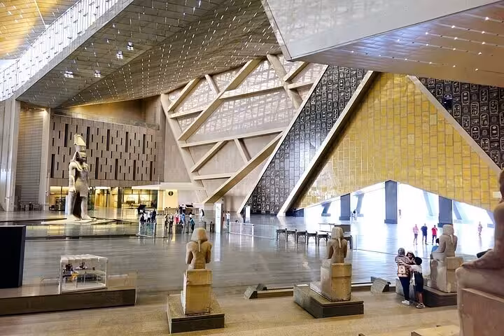 Inside Grand Egyptian Museum main hall in Giza with statues and modern architecture on half-day tour