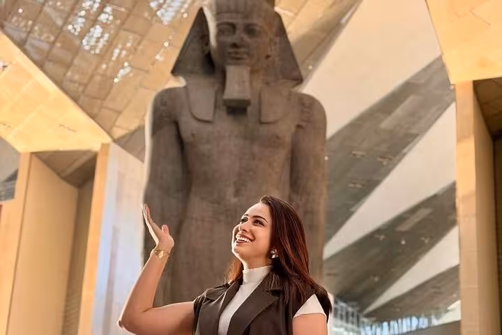 Traveler admiring a colossal pharaoh statue inside the Grand Egyptian Museum on a Giza Pyramids tour