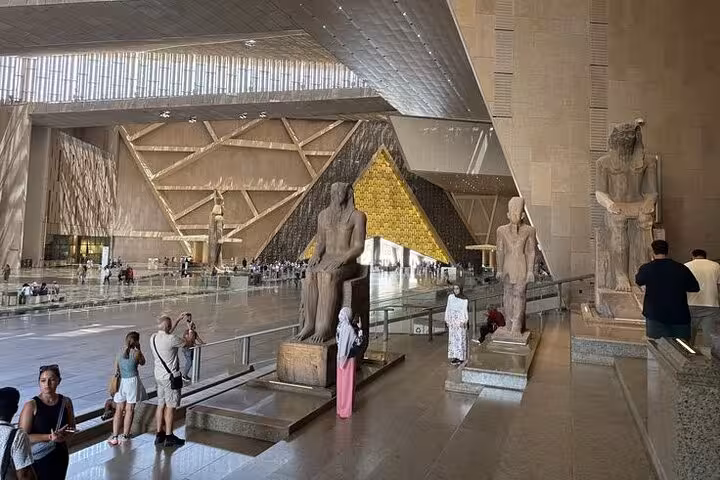 Grand Egyptian Museum atrium with colossal pharaoh statues, Cairo stop on Hurghada small group tour