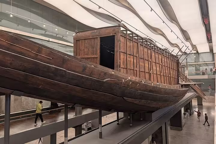 Ancient wooden solar boat exhibit at the Grand Egyptian Museum on a half-day Cairo tour with tickets