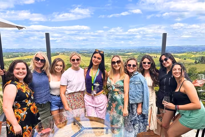 Tour group posing with scenic vineyard views on Tuscany wine tour from Florence.