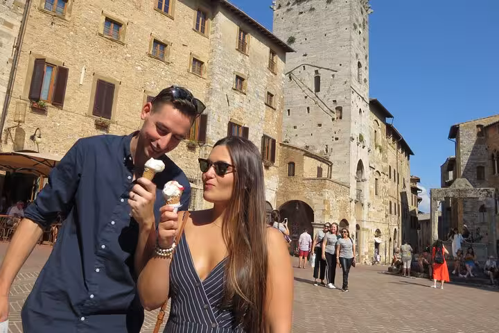 Tourists enjoying gelato in the historic town square of San Gimignano during a Tuscany wine tour.
