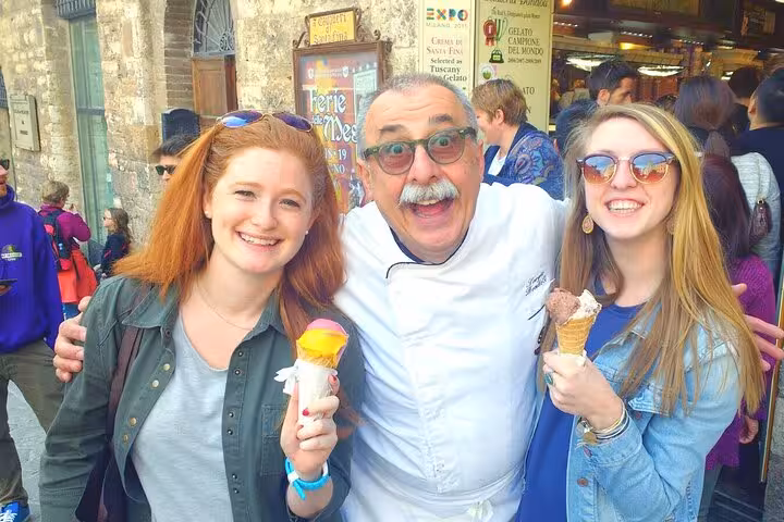 Tourists enjoying gelato with a friendly local in San Gimignano, Tuscany during a wine tour from Florence.