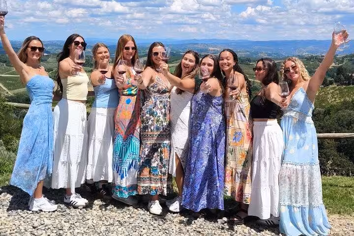 Group of women celebrating with wine glasses against the backdrop of Tuscany's stunning landscape.