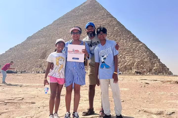 Group photo at the Great Pyramid of Giza holding Egypt Tours Club sign on Giza and Saqqara private tour from Cairo