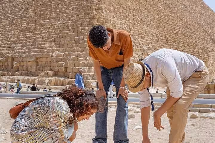 Tourists examine ancient stones at the Great Pyramid of Giza on a guided pyramid interior and Sphinx tour