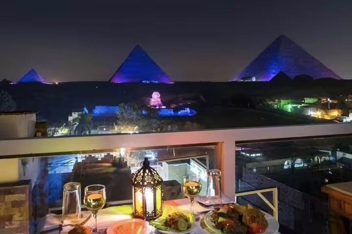 Candlelit dinner at Great Pyramid Inn terrace with illuminated Giza Pyramids night view and drinks