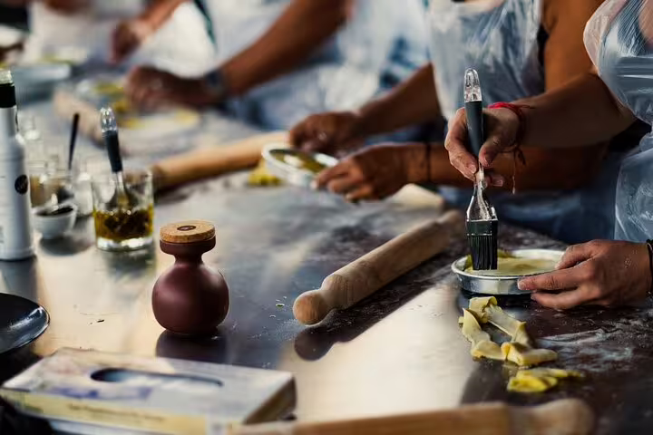 Hands-on Greek cooking class in Athens shaping dough at a kitchen station, preparing rooftop dinner with Acropolis view