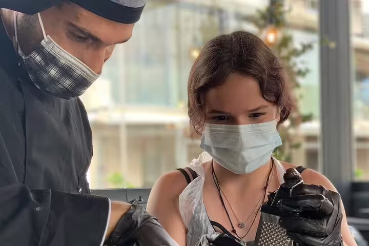 Chef guiding guest with grater in Athens Greek cooking class, before rooftop dinner with Acropolis view