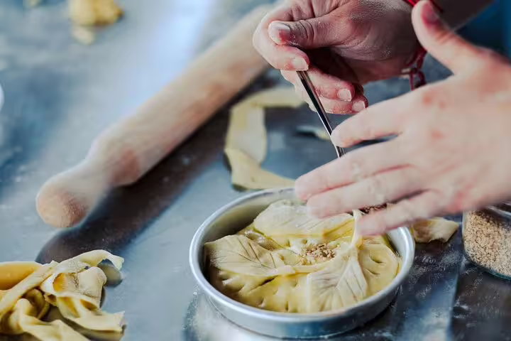 Shaping traditional Greek pie in a pan during Athens cooking class, part of rooftop dinner with Acropolis view