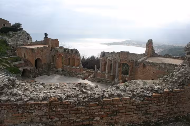 Ancient ruins of the Greek Theatre in Taormina overlooking the stunning Mediterranean Sea, ideal for history enthusiasts.