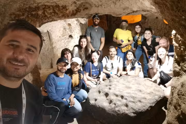 Green Tour group photo inside Cappadocia underground city cave chamber on full-day guided excursion