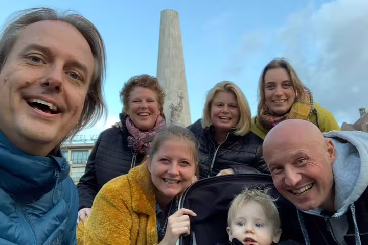 Group selfie at Amsterdam National Monument during a self-guided e-scavenger hunt city exploration
