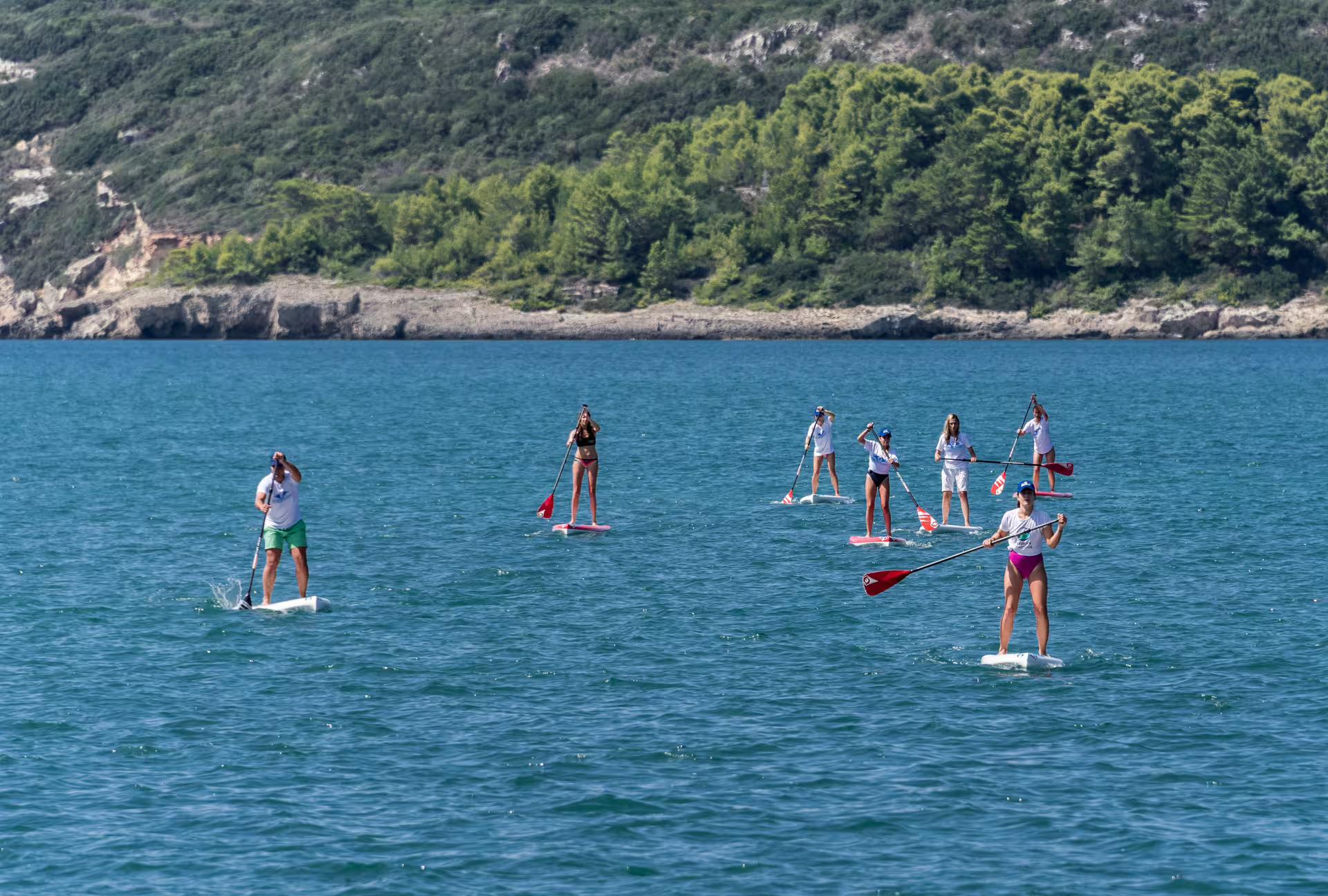 Group stand up paddleboarding on the clear sea near Kardamyli, Mani coast, guided SUP tour in Greece