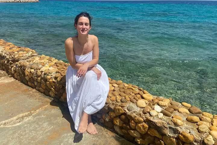 Guest sitting on a stone seawall at Ain El Sokhna, clear Red Sea water on a day tour from Cairo