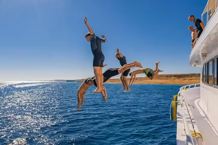 Guests jumping off a yacht into the Red Sea on a Hurghada Dolphin House snorkeling trip and swim stop