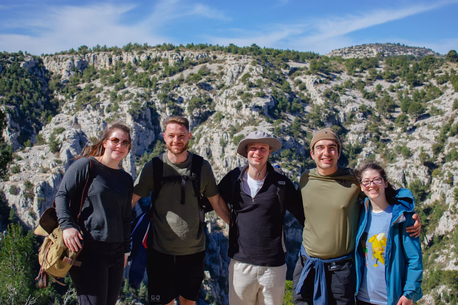 Happy hikers on guided Calanques National Park hike from Luminy, posing with limestone cliffs near Marseille