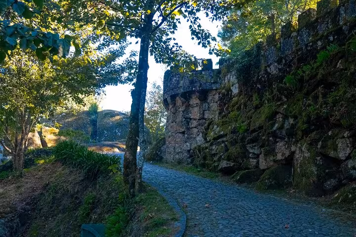 Cobblestone pathway alongside ancient stone walls and lush greenery in Guimarães, ideal for exploring on a private tour.