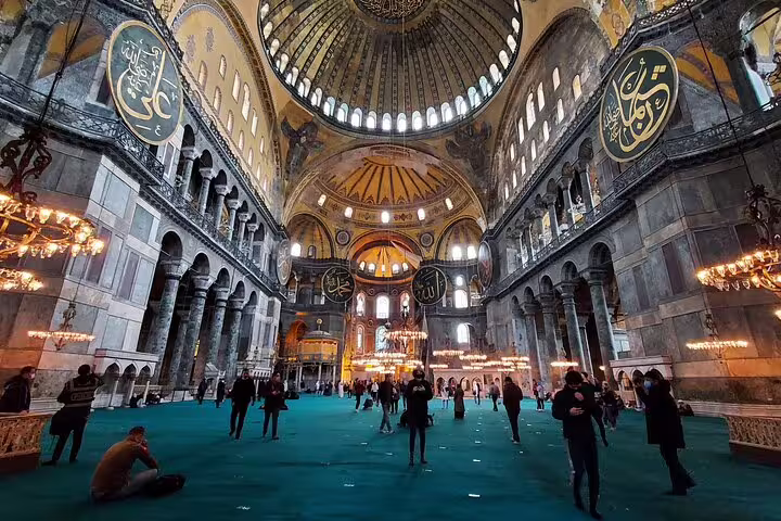 Visitors explore the grand interior of Hagia Sophia with its stunning domes and Islamic calligraphy in Istanbul.