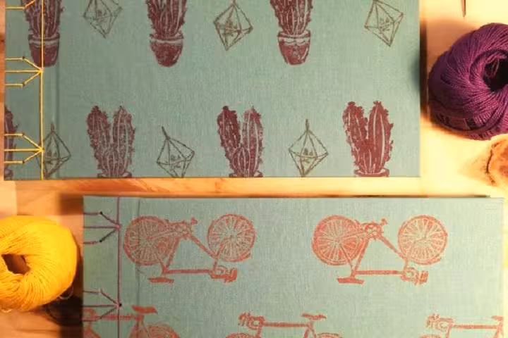Handmade stitched journals with patterned covers and colorful thread at a Vieux Port bookbinding workshop