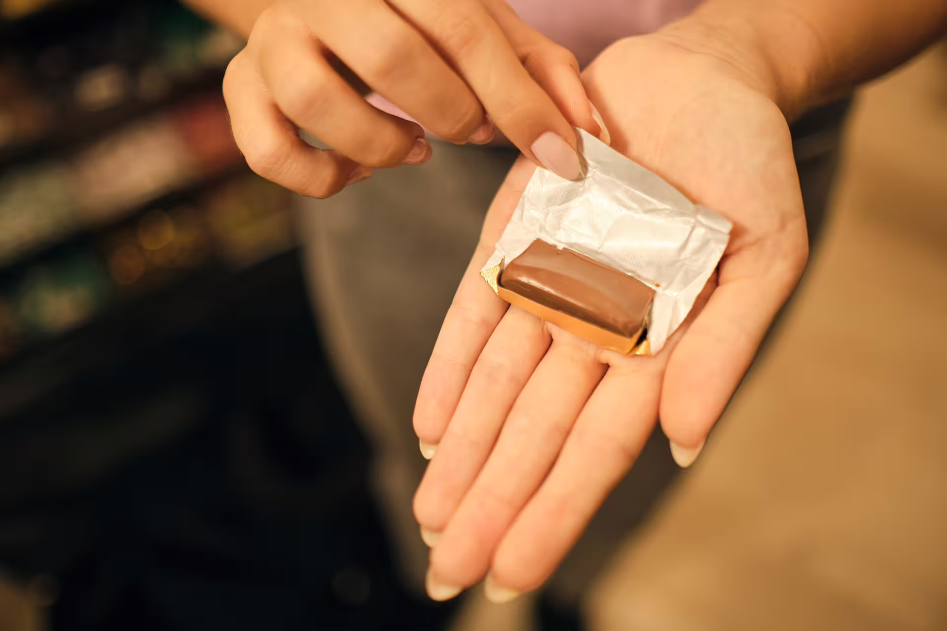 Hands unwrapping a Torino chocolate praline on the Turin chocolate tasting experience, sampling local sweets