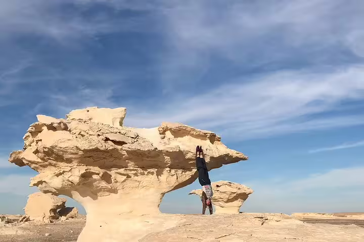 Handstand under mushroom rock in Egypt White Desert, iconic stop on 3 days 2 nights Bahariya Oasis desert tour