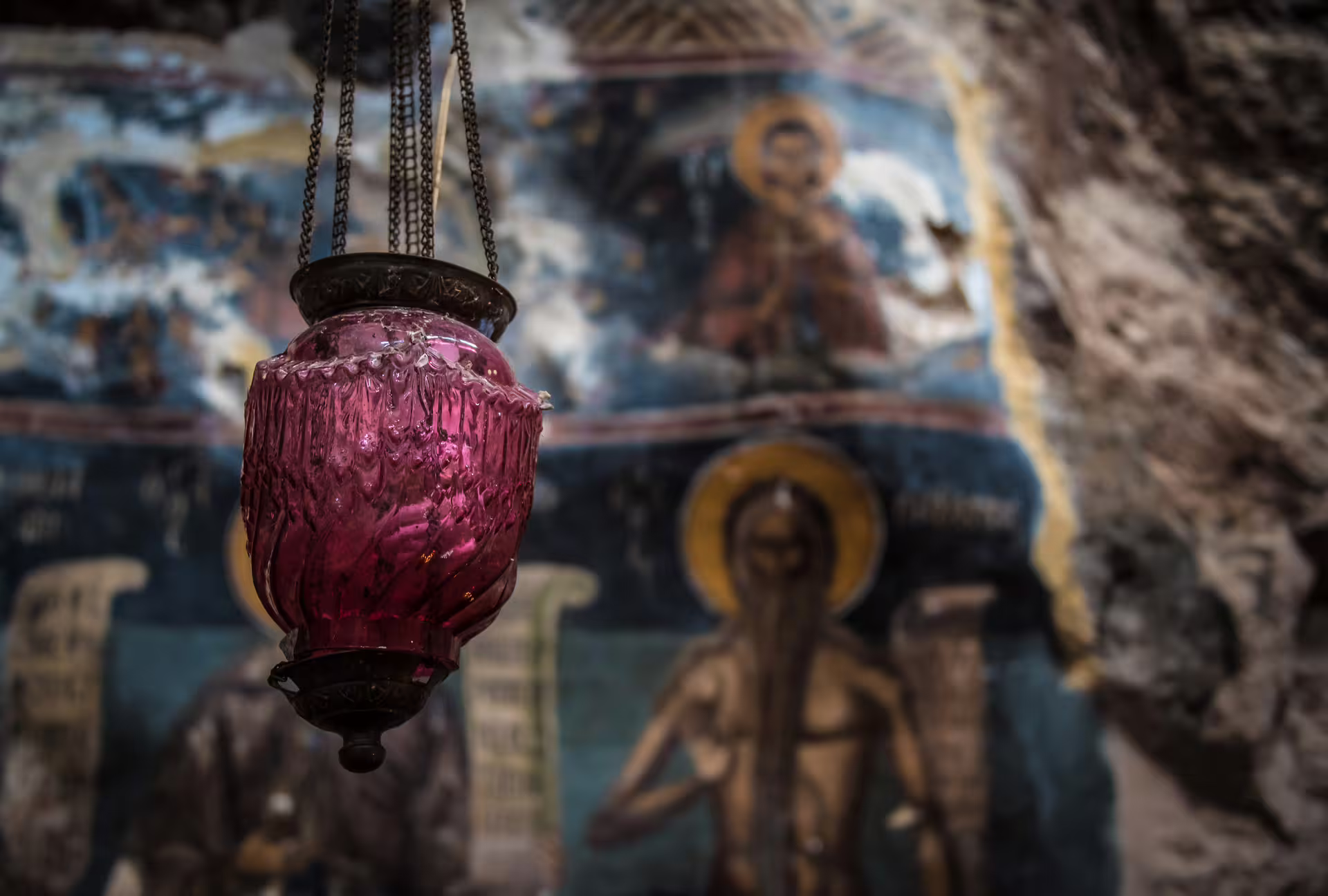 Hanging red glass lantern inside cliffside monastery on the Hiking Lousios Gorge trail in Arcadia, Greece