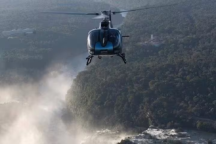 Helicopter soaring above lush Foz de Iguaçu landscape with mist and river views, capturing breathtaking aerial vistas.