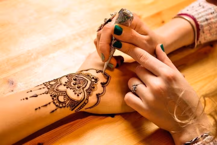 Intricate henna design being applied on a hand, showcasing cultural art in Abu Dhabi desert safari experience.