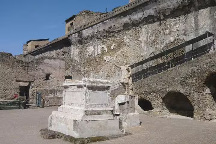 Marble altar and arched chambers set against weathered cliff walls at Herculaneum ruins visited on a private half-day tour
