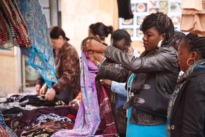 Visitors explore vibrant textiles at a bustling Parisian market, a hidden gem in the city's undiscovered quarters.