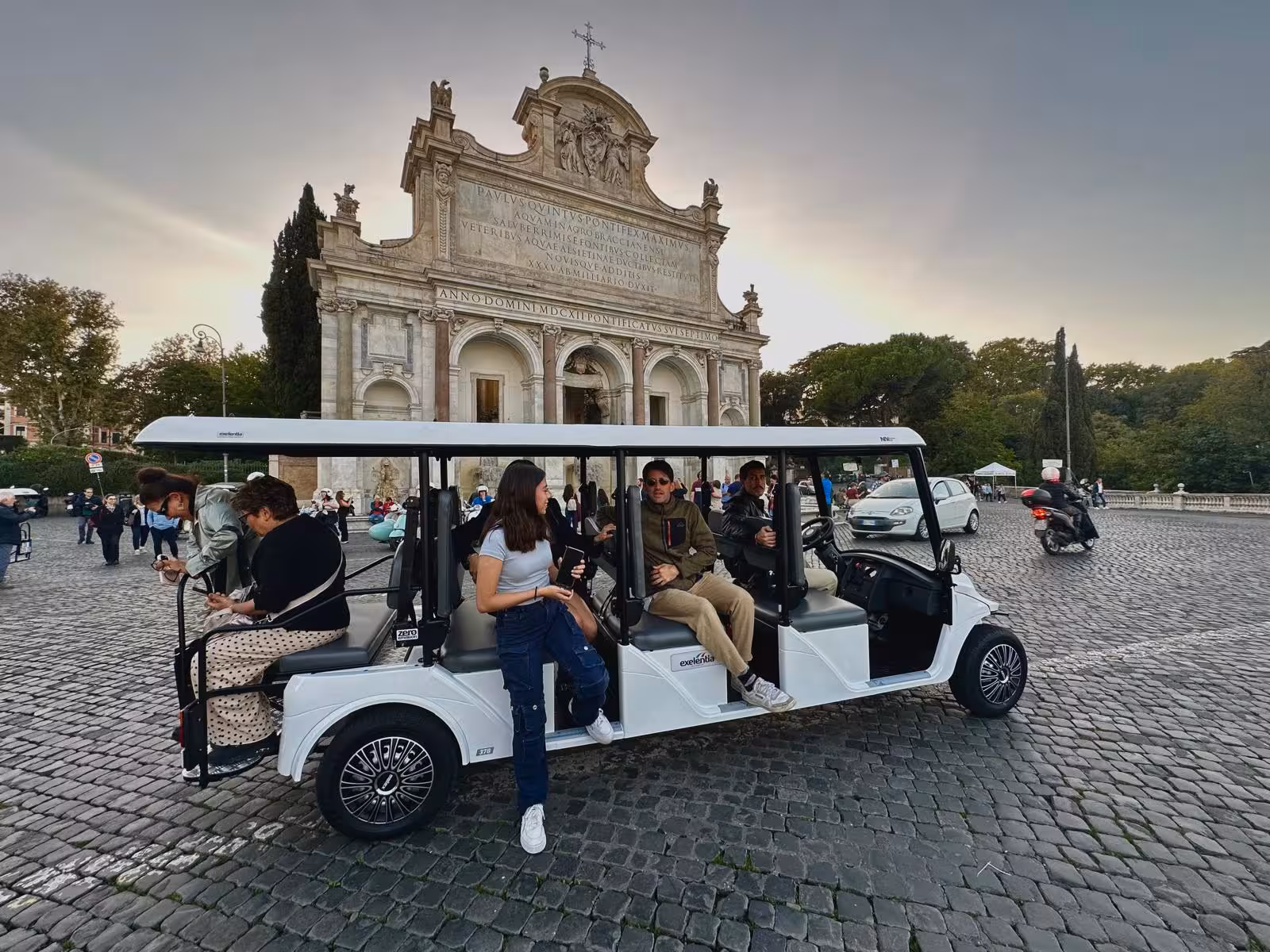 Tourists enjoying a scenic golf cart tour near a historic Roman landmark at sunset in Hidden Rome.