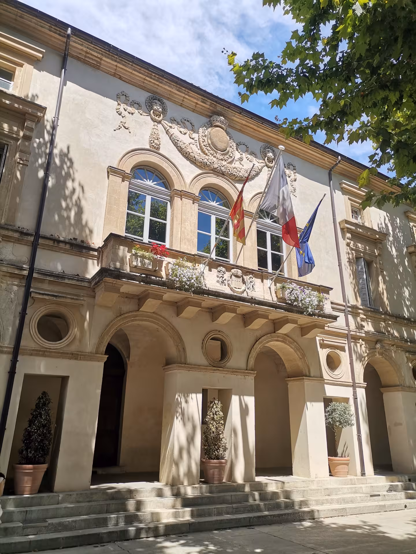 Historic Arles town hall facade with French and EU flags, classic Provence architecture on guided tour