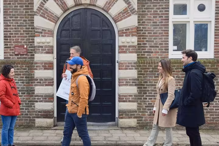 Small group strolls past brick facades and arched door in Hoorn, Netherlands, on a 2-hour history walking tour