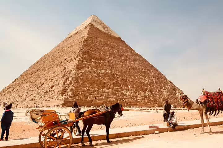 Horse-drawn carriage beside the Great Pyramid of Giza on a half-day tour in Cairo, Egypt desert