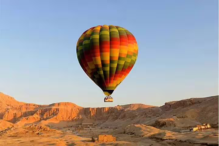 Colorful hot air balloon floating above Luxor mountains at sunrise on a Luxor balloon ride with transfer