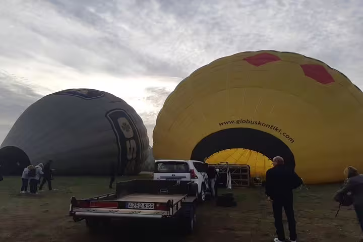 Hot air balloons being prepared for flight at a scenic launch site in Igualada, perfect for an unforgettable balloon tour.